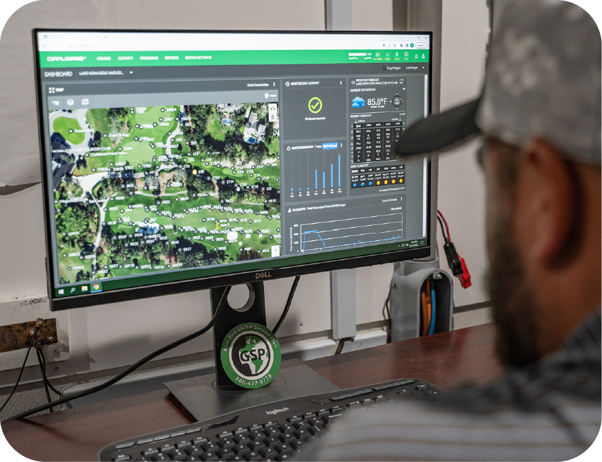 A man with a beard in a gray baseball cap and polo looks at his monitor, showing golf course irrigation data and an overhead satellite map.