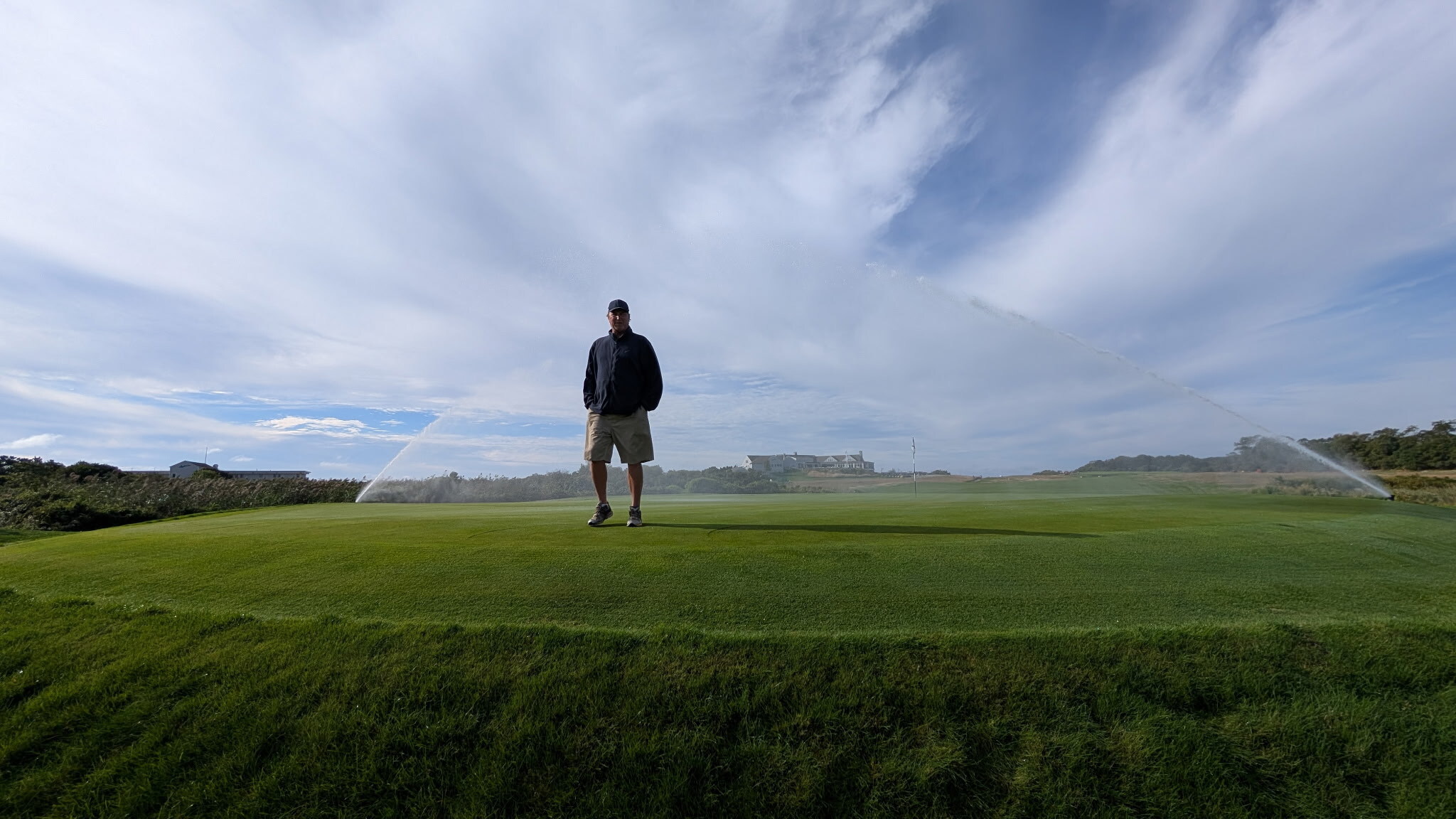 Superintendent standing on green with Rain Bird 952 LT Rotors spraying in the background