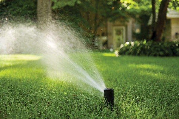 sprinkler on grass with home in background
