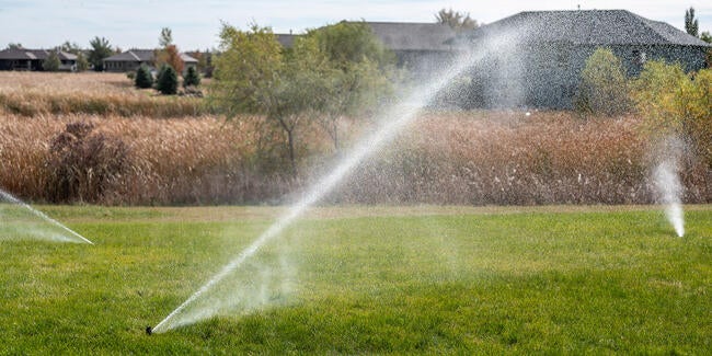 blowing out the sprinkler system in a lawn