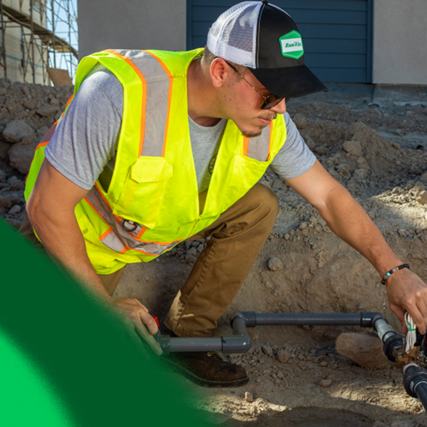 a male working on installing an irrigation pipe system.