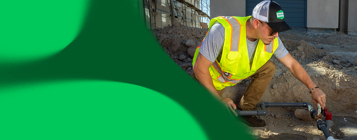 A male worker installing an irrigation system pipe system.