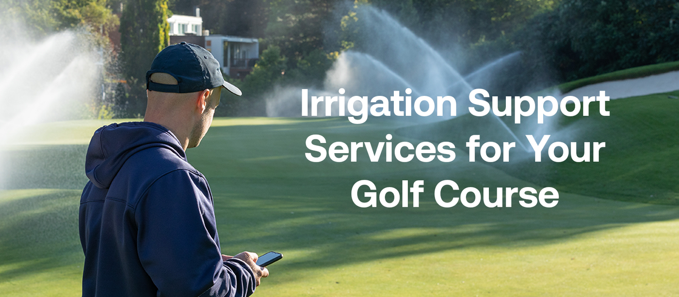 Man standing on a golf course, back facing to viewer and holding a smartphone while looking at running irrigation sprinklers.
